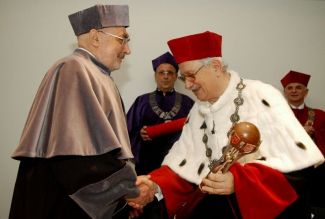 Prof. Jan Krysiński, TUL rector, in red gown and white ermine is congratulating Prof. Marek Trombski the DHC title of TUL. He is holding a scepter in his left hand.