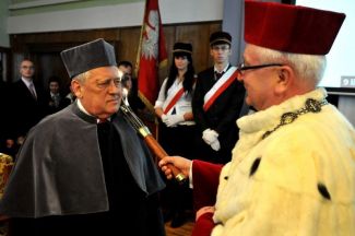 Prof. Stanisław Bielecki, TUL rector, in red gown and white ermine is resting a scepter on the shoulder of Prof. Stanisław Liszewski in grey gown and is awarding him the DHC title of TUL. 
