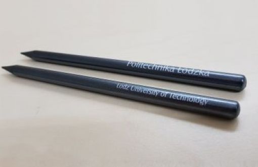 Dwa czarne ołówki z napisem Politechnika Łódzka położone równolegle na jasnym tle.