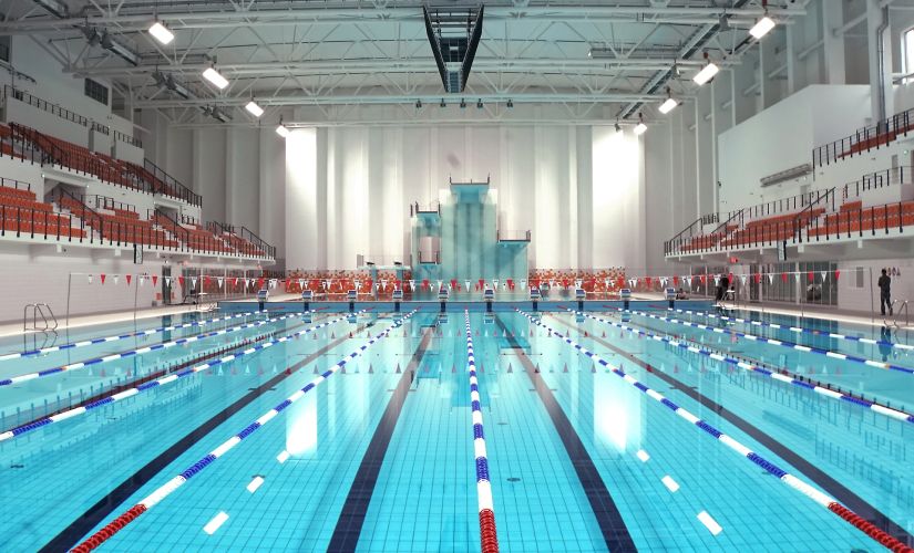 Tory, 50 m basenu wypełnionego wodą. Po bokach trybuny z pomarańczowymi krzesełkami.