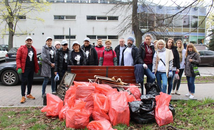 Uczestnicy akcji sprzątania świata. Przed nimi czerwone worki wypełnione śmieciami.