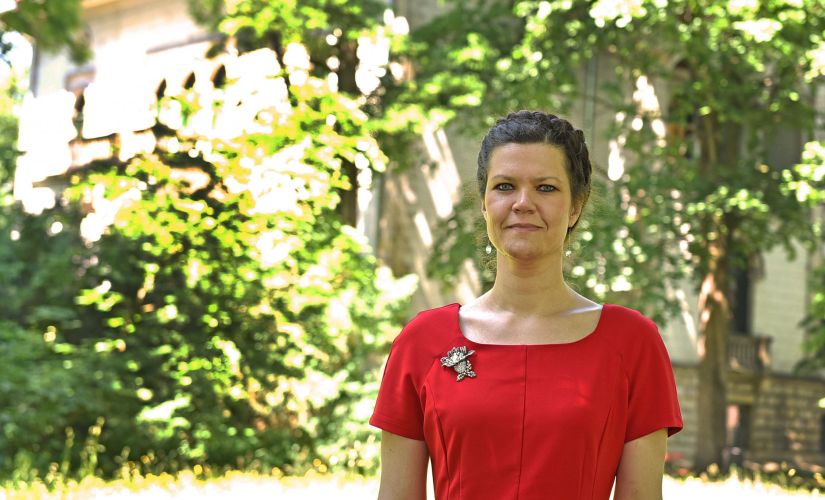 Zdjęcie portretowe: prof. Anna Fabjańska w czerwonej sukience na tle zieleni.