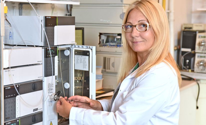 prof. Grażyna Leszczyńska w białym fartuchu przy aparaturze chemicznej.