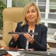 Portrait photo. Smiling Professor Renata Kotynia is sitting at her desk in her office. In her hands she holds a metal construction element.