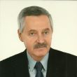Zdjęcie portretowe: prof. dr hab. Krzysztof Piotr Marynowski w ciemnej marynarce, niebieskiej koszuli i krawacie na jasnoszarym tle.