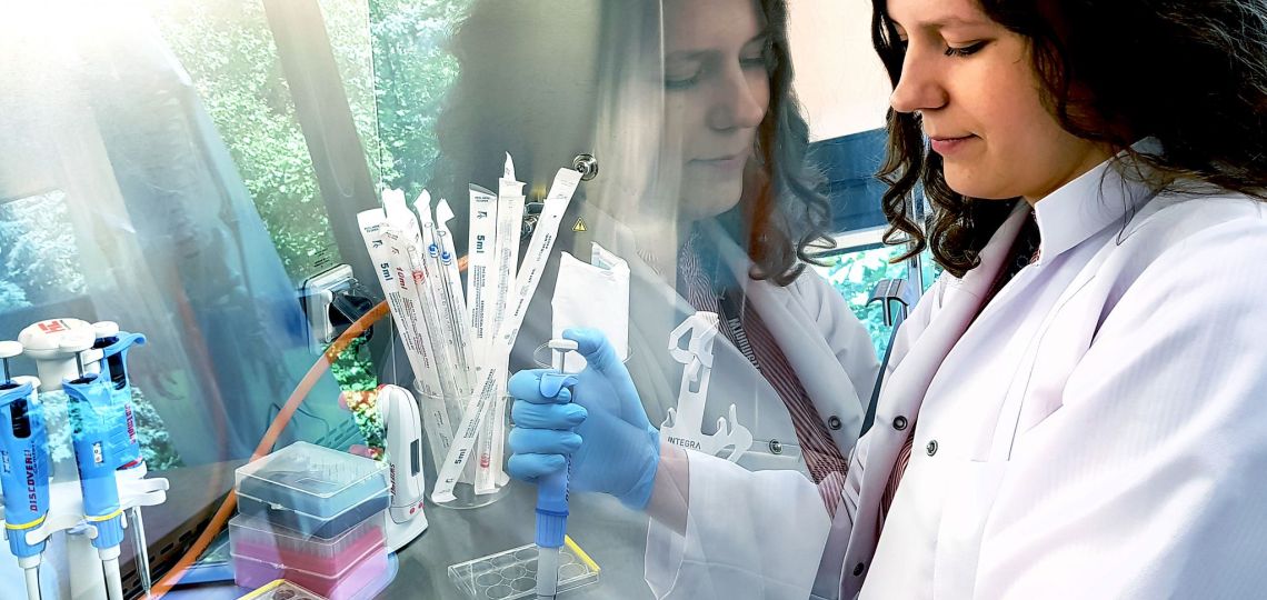 Naukowiec z PŁ przy chemicznym stanowisku laboratoryjnym. Doświadczenie wykonuje za przeźroczystą szybą bezpieczeństwa.