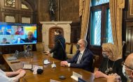 Gabinet Rektora PŁ: drewniany stół przy którym siedzi kilka osób skierowanych w stronę ekranu telewizora na którym widać postacie z uniwersytetu z ENSAM.