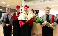 W reprezentacyjnej auli od prawej strony stoją w togach: prof. Klaus Müllen, który trzyma bukiet róż, prof. Krzysztof Jóźwik, prof. Łukasz Albrecht i prof. Jacek Ulański.