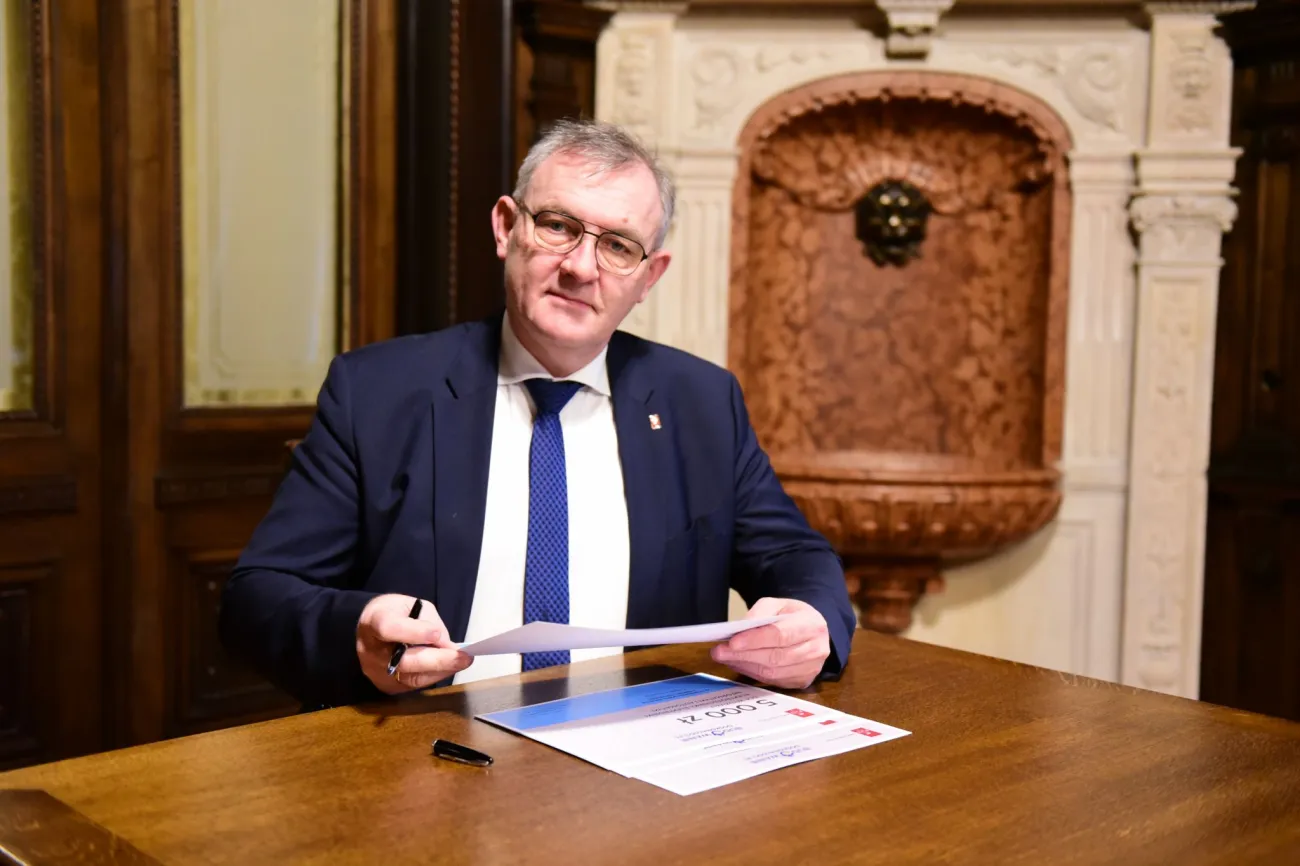 Prof. Krzysztof Jóźwik, rektor PŁ, siedzi przy biurku w swoim gabinecie i podpisuje dokumenty.