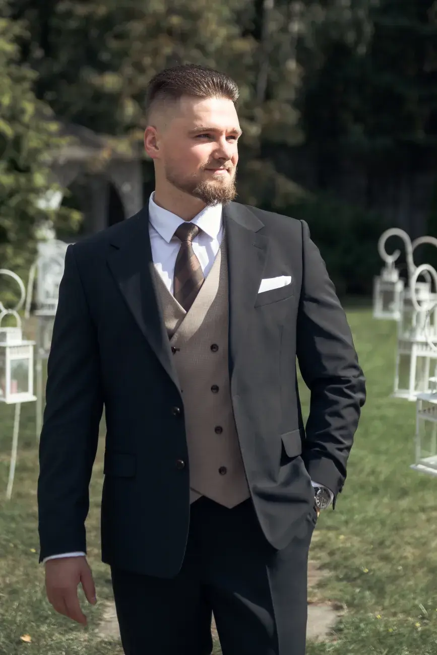 młody mężczyzna w eleganckim stroju na tle plenerowej dekoracji uroczystościowej
