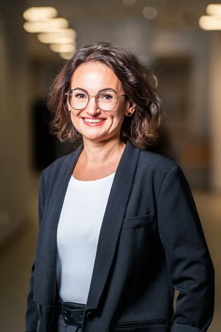 uśmiechnięta Agnieszka Wosia, prof. uczelni, PŁ, stoi na tle głębi korytarza