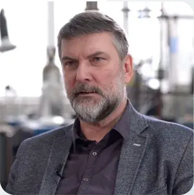 portret mężczyzny z brodą, w szarym garniturze, w tle laboratorium jasne, prof. Dariusz Bieliński