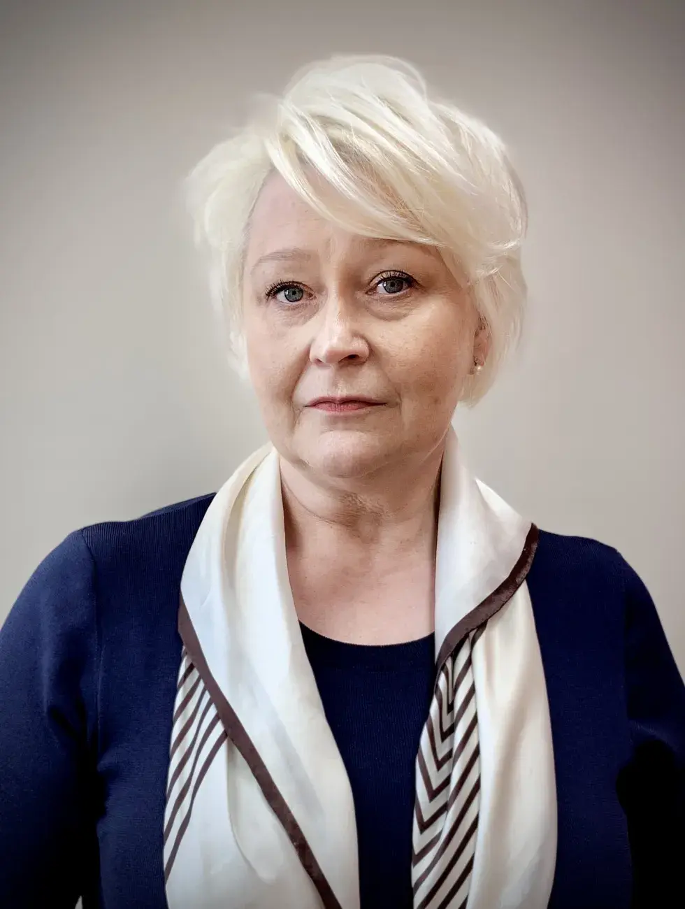 portret kobiety z blond włosami, w apaszce, granatowym ubraniu, na jasnym tle
