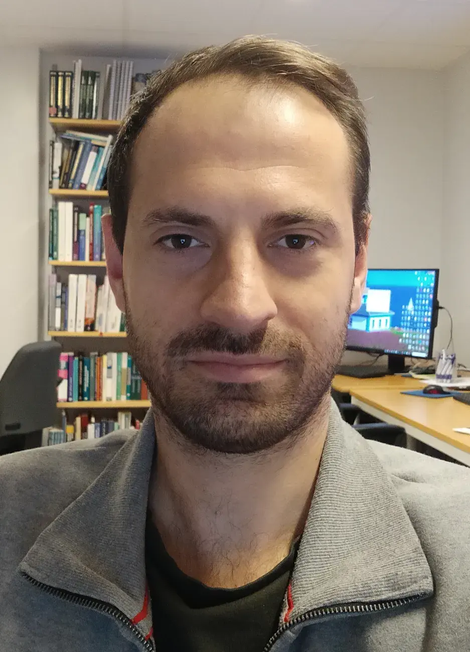dr inż. Jakub Jurek, zdjęcie portretowe, w tle biblioteczka i monitor