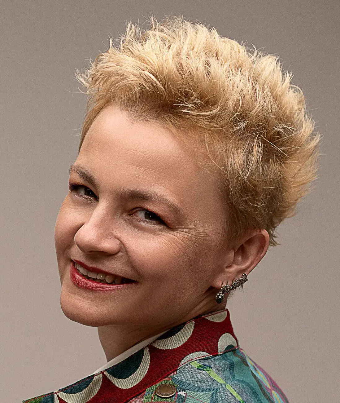 portret uśmiechniętej kobiety z krótkimi blond włosam, w tle beżowa ściana, Małgorzata Zakłos-Szyda