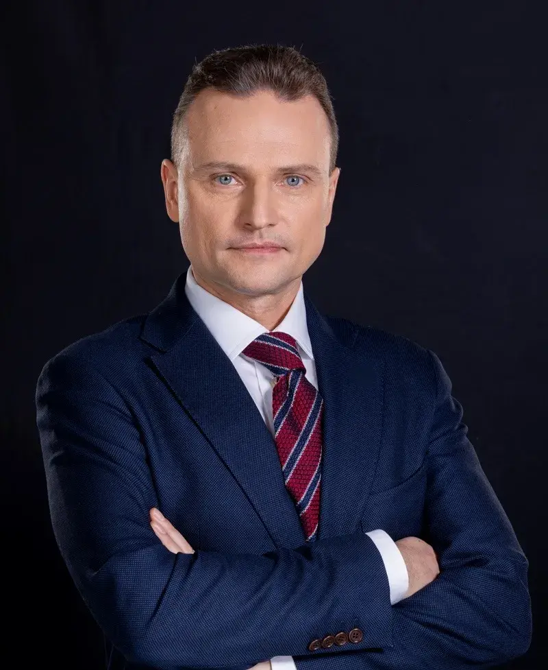 portret mężczyzny w garniturze z założonymi rękoma, ciemne tło, Michał Domińczak
