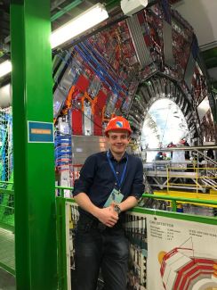 Zdjęcie portretowe: Michał Maciejewski w czerwonym kasku w hali Europejskiej Organizacji Badań Jądrowych CERN