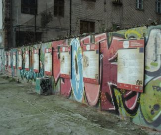 Wall with ugly graphics. Shabby buildings in the background.