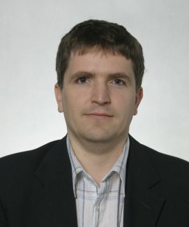 Portrait photo: Dr Eng. Łukasz Frącczak in a dark jacket against a white background.