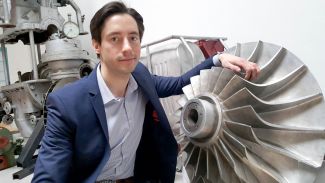 Portrait photo: Dr Eng Grzegorz Liśkiewicz in his jacket is standing next to a grey construction element.