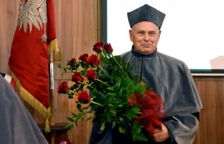 Prof. Peter Hagedorn in gown and with a bunch of roses at the ceremony of awarding the DHS title of TUL