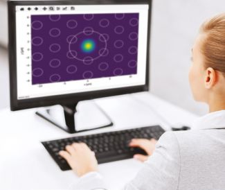 Computer screen showing unevenly spaced circles on a purple background. Also visible is a fragment of a woman in a white lab coat working on a computer.