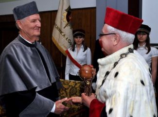 Prof. Stanisław Bielecki, TUL rector, in red gown and white ermine is congratulating Prof. Andrzej Ajdukiewicz the DHC title of TUL. He is holding a scepter in his left hand.