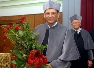 Portrait photo: Prof. Arun Sadashiv Mujumdar in grey gown and with a bunch of roses at the ceremony of awarding the DHC of TUL.