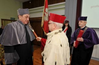 Prof. Stanisław Bielecki, TUL rector, in red gown and white ermine is resting a scepter on the shoulder of Prof. Bogdan Marciniec in grey gown and is awarding him the DHC title of TUL.