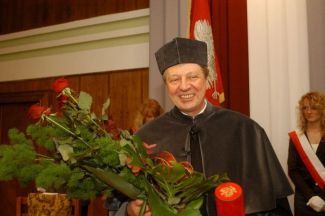 Zdjęcie portretowe: prof. Krzysztof Matyjaszewski w szarej todze i bukietem róż w dłoniach podczas uroczystości nadania DHC PŁ. 