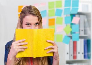 Overview photo: a girl hides behind a book with a yellow cover.