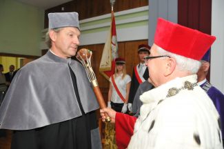 Prof. Stanislaw Bielecki, TUL Rector, in a red gown and white ermine, holds a sceptre on the shoulder of Prof. Anatoly Leonidovich Gavrikov in a grey gown and confers on him the title of Doctor Honoris Causa of Lodz University of Technology.