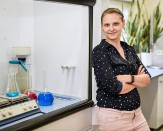 Dr inż. Marta Gmurek stoi przy chemicznym stanowisku laboratoryjnym.