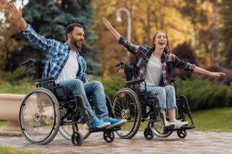 A man and woman in wheelchairs with their arms spread out - pretending to fly.