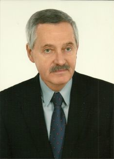 Zdjęcie portretowe: prof. dr hab. Krzysztof Piotr Marynowski w ciemnej marynarce, niebieskiej koszuli i krawacie na jasnoszarym tle.