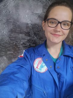 Zdjęcie portretowe: Aleksandra Wilczyńska, studentka PŁ, w niebieskiej kurtce na ciemnym tle.
