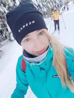 Mgr inż. Monika Bartczak w zimowej czapce i zielonym polarze na trasie dla narciarzy-biegaczy.