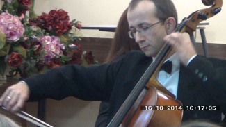 Assoc. Prof. Eng. Bartłomiej Stasiak wearing a tailcoat, plays the cello during a concert.