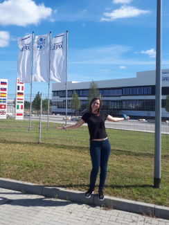 Weronika Głowadzka w słoneczny dzień stoi przed budynkiem laboratorium w Niemczech.