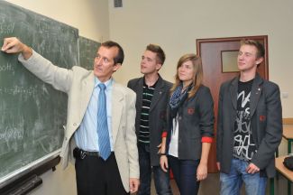 Dyrektor Tomasz Kozera z uczniami przy tablicy.