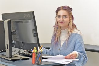 Anna Walczak siedzi przy biurku z komputerem