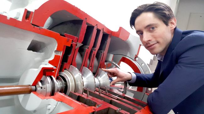 Zdjęcie poglądowe: dr inż. Grzegorz Liśkiewicz w laboratorium. Po lewej stronie urządzenie pomiarowe w kolorze czerwonym.