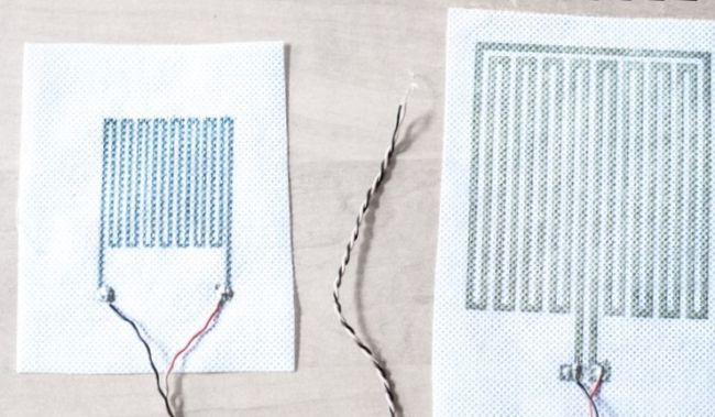 Two white fabrics covered with regular black designs produced using digital printing technology.