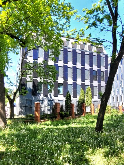 Frontowa ściana budynku pasywnego PŁ wśród zieleni.