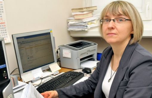 Zdjęcie portretowe: dr inż. Janina Leks-Stępień siedzi przy biurku. W tle dokumenty, komputer i drukarka.