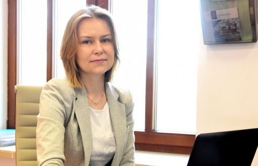 Zdjęcie portretowe: dr inż. Edyta Marcinkiewicz siedzi w gabinecie przy biurku i otwartym laptopie.