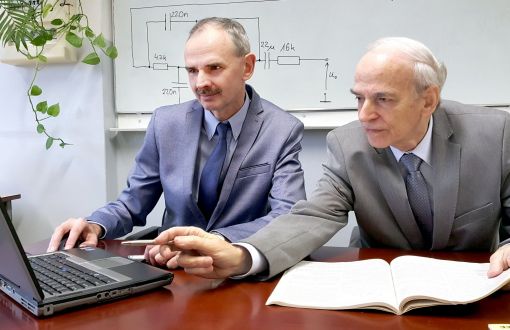 Portrait photo: Prof. Dr. Michał Tadeusiewicz Assoc. Prof. Eng. and Assoc. Prof. Eng. Stanisław Hałgas, TUL Prof. in their suits sitting at their desks and working on the laptop.