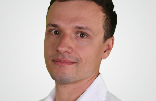 Zdjęcie portretowe: dr hab. inż. Piotr Brzeski w białej koszuli na jasnym tle.