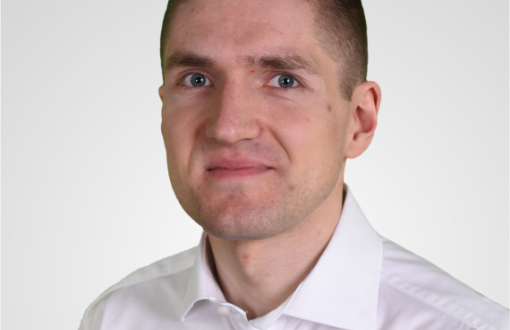 Zdjęcie portretowe: dr Dawid Dudkowski w białej koszuli na jasnym tle.