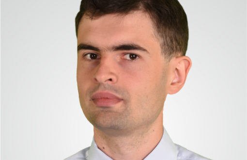 Zdjęcie portretowe: dr inż. Piotr Leśniewski w białej koszuli na jasnym tle.